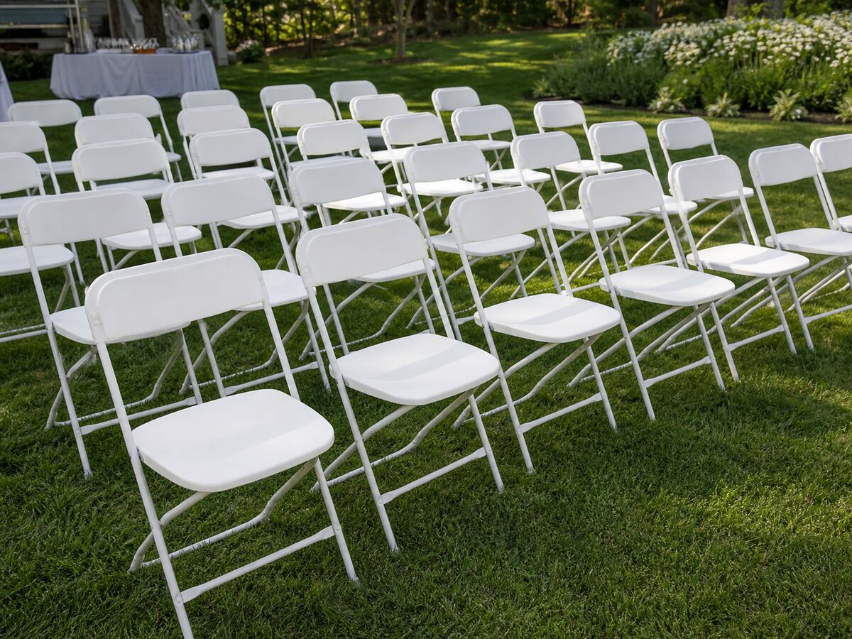 White plastic folding chairs with steel frames set up at outdoor event